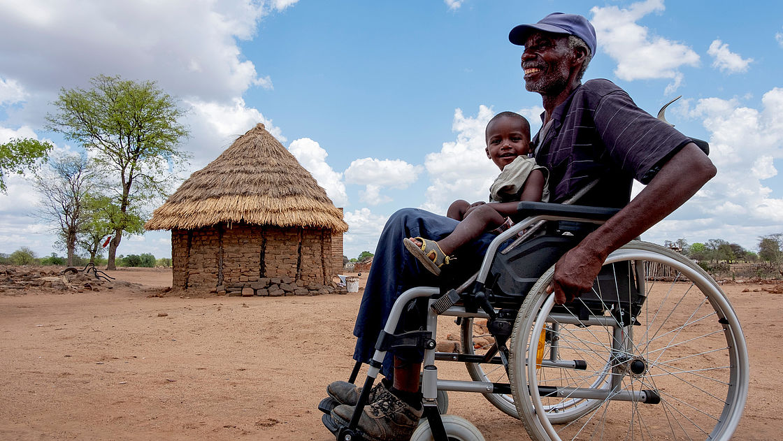 Ezekiel gives his grandson Kuda a ride in his new wheelchair at his home in a food-insecure area of Zimbabwe. 